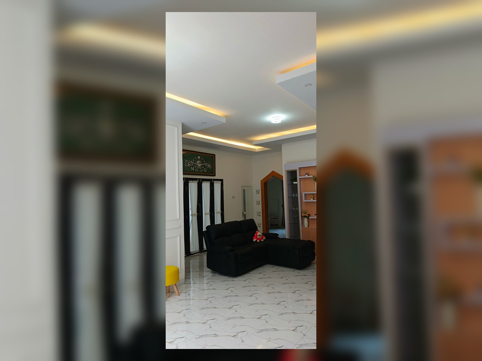 Ruang keluarga rumah hunian Jalan Majang dengan plafon drop ceiling dan sofa